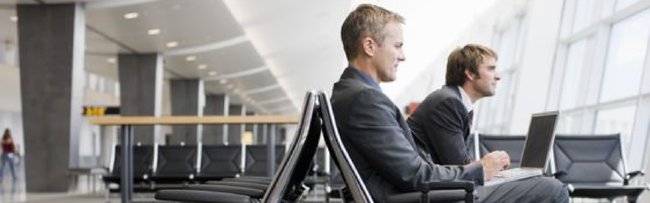 Duty of Care: Shared Responsibility Between Travelers and Travel Managers 7 two man waiting for their plane in the airport, meanwhile they work.