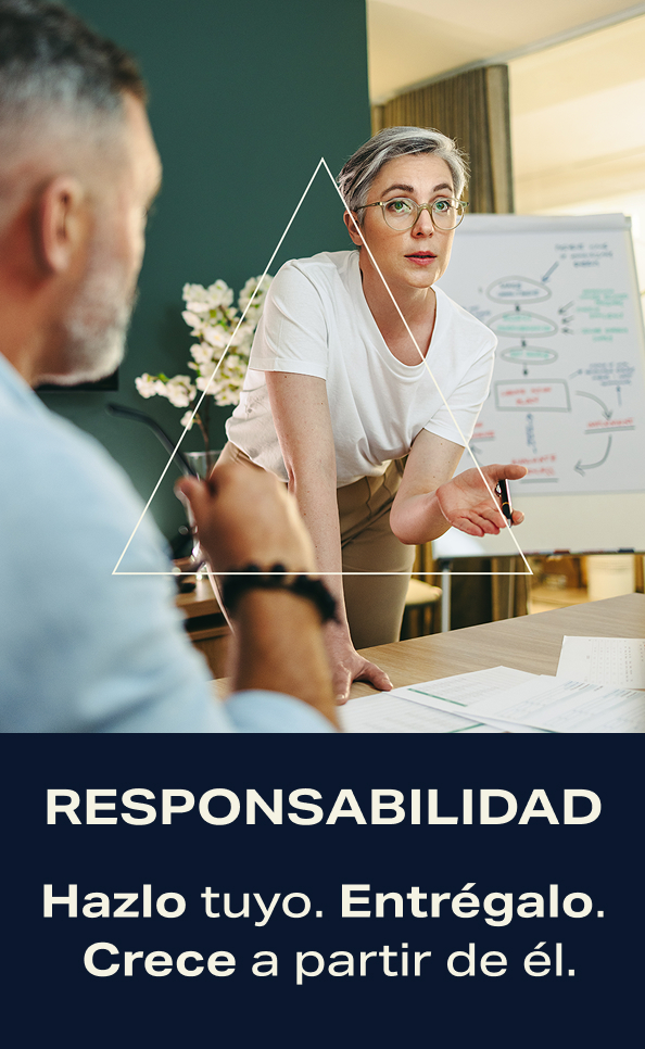 Responsabilidad. Hazlo tuyo. Entrégalo. Crece a partir de él. Dos compañeros de trabajo, en un escritorio, conversando sobre alguna tarea.